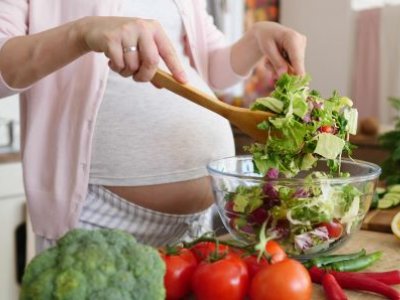 A pregnant woman makes a healthy salad.